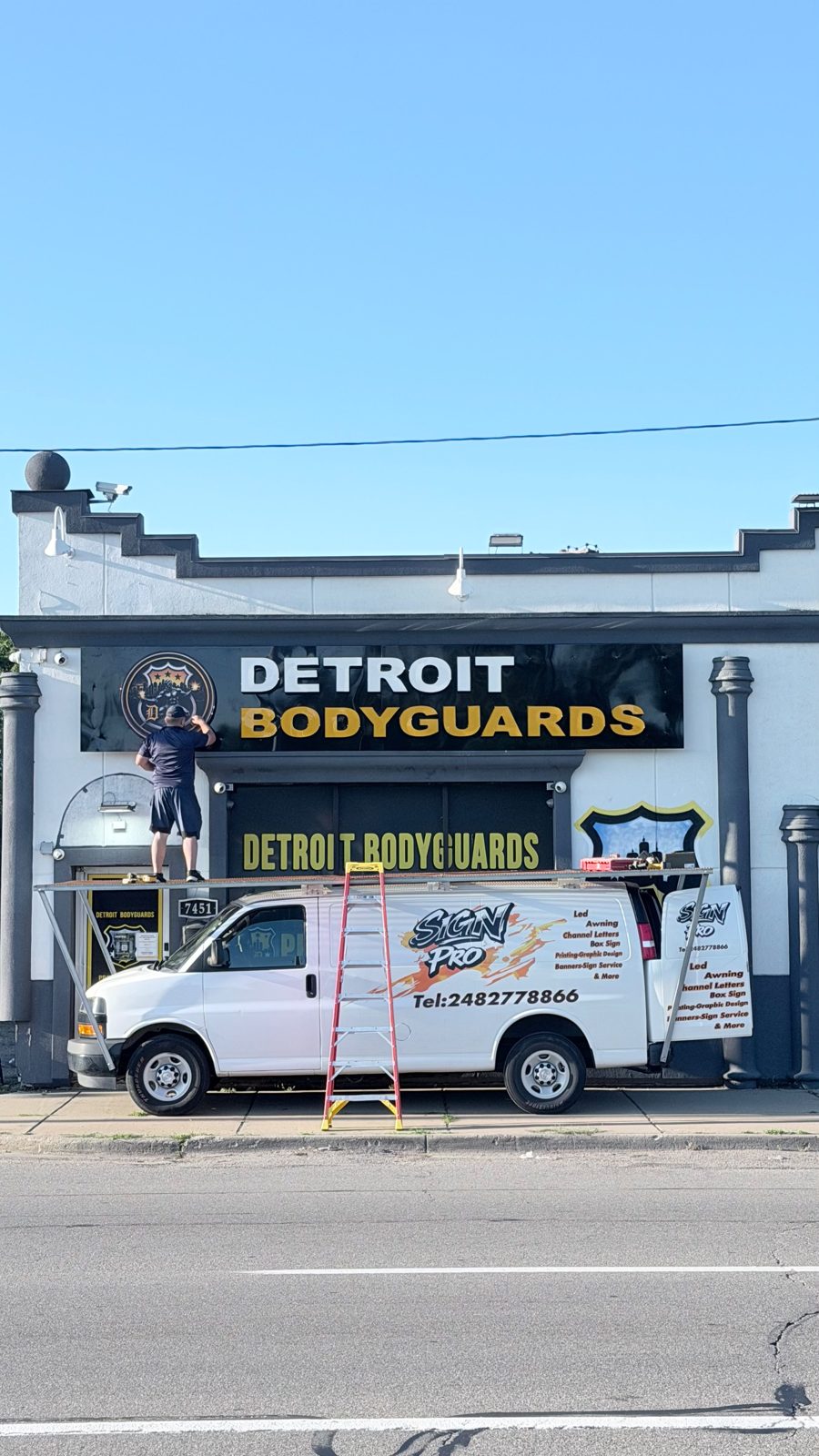 Sign Pro crew installing the Detroit Bodyguards sign with the Sign Pro van
